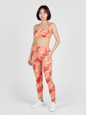 FTFO || BIG BRAND LOW PRICE model wearing a vibrant red and yellow kaleidoscopic print Adidas x FARM Rio sports bra set