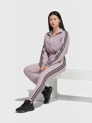 Model wanita mengenakan Adidas Future Icons 3-Stripes legging berwarna ungu muda dengan aksen tiga garis hitam