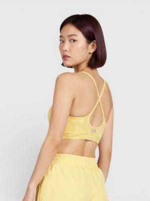 Model wanita mengenakan sport bra kuning Adidas All Me dari FTFO || BIG BRAND LOW PRICE dengan desain strappy belakang