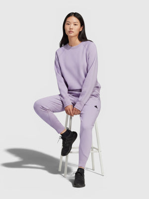 Model wanita mengenakan setelan Adidas W Z.N.E. WTR PT berwarna ungu muda yang nyaman dan stylish untuk olahraga.