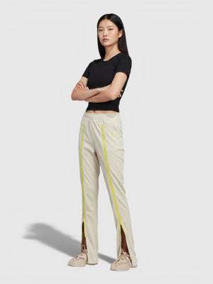 Model mengenakan celana track pants FTFO || BIG BRAND LOW PRICE berwarna krem dengan detail ritsleting neon vertikal