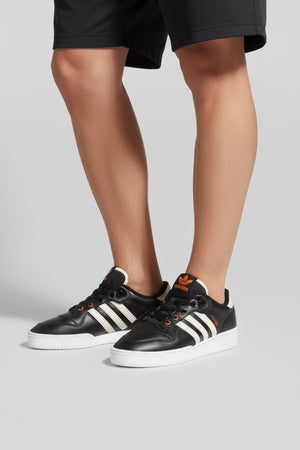 RIVALRY LOW W (RIVALRY) Adidas Rivalry Low W adalah sepatu ikonik yang membawa nuansa nostalgia basket era 80-an langsung ke