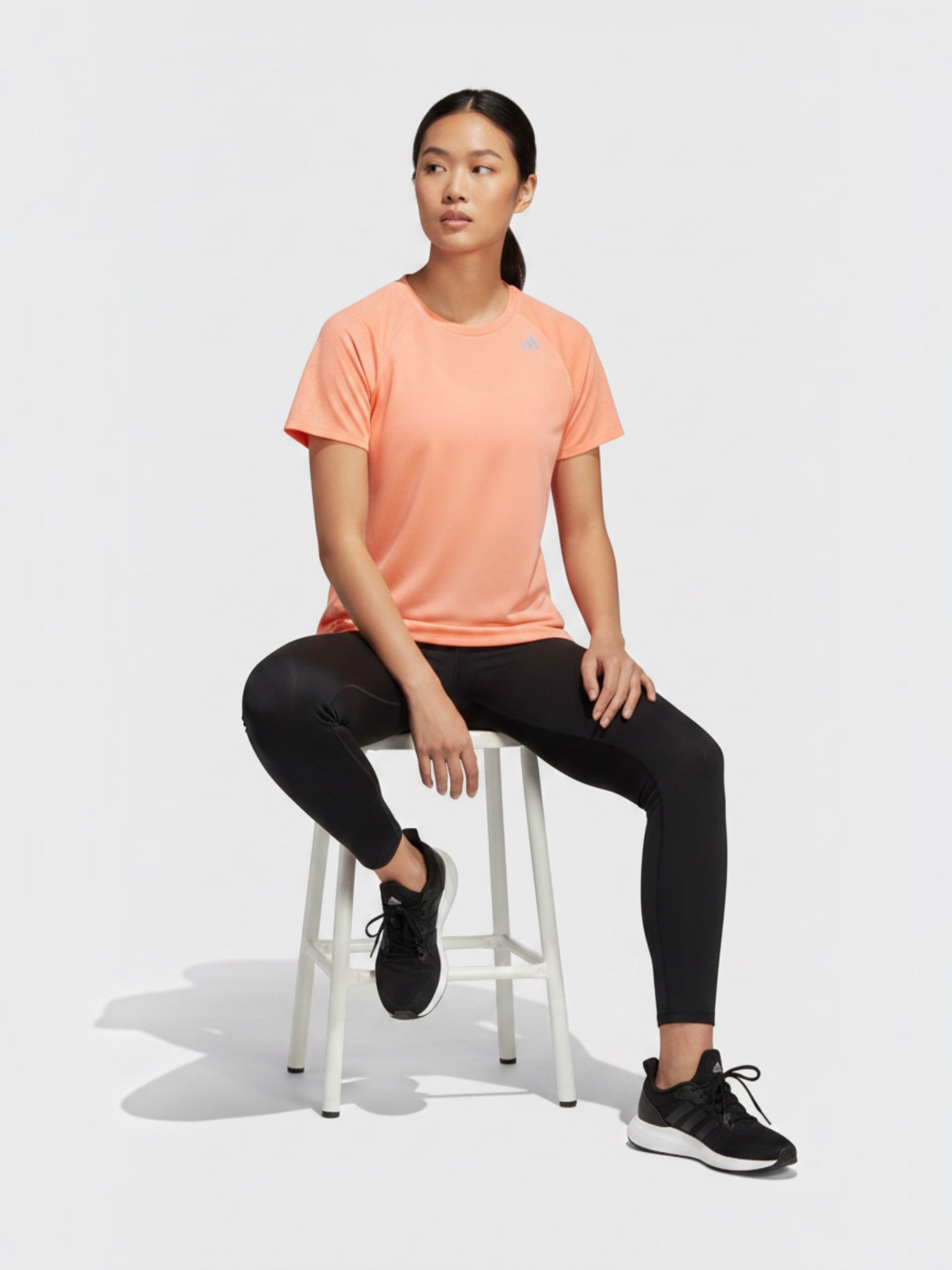 FTFO || BIG BRAND LOW PRICE Adidas Adizero peach perforated running tee on a model sitting on a white stool