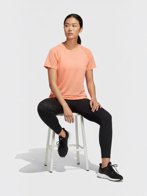 FTFO || BIG BRAND LOW PRICE Adidas Adizero peach perforated running tee on a model sitting on a white stool