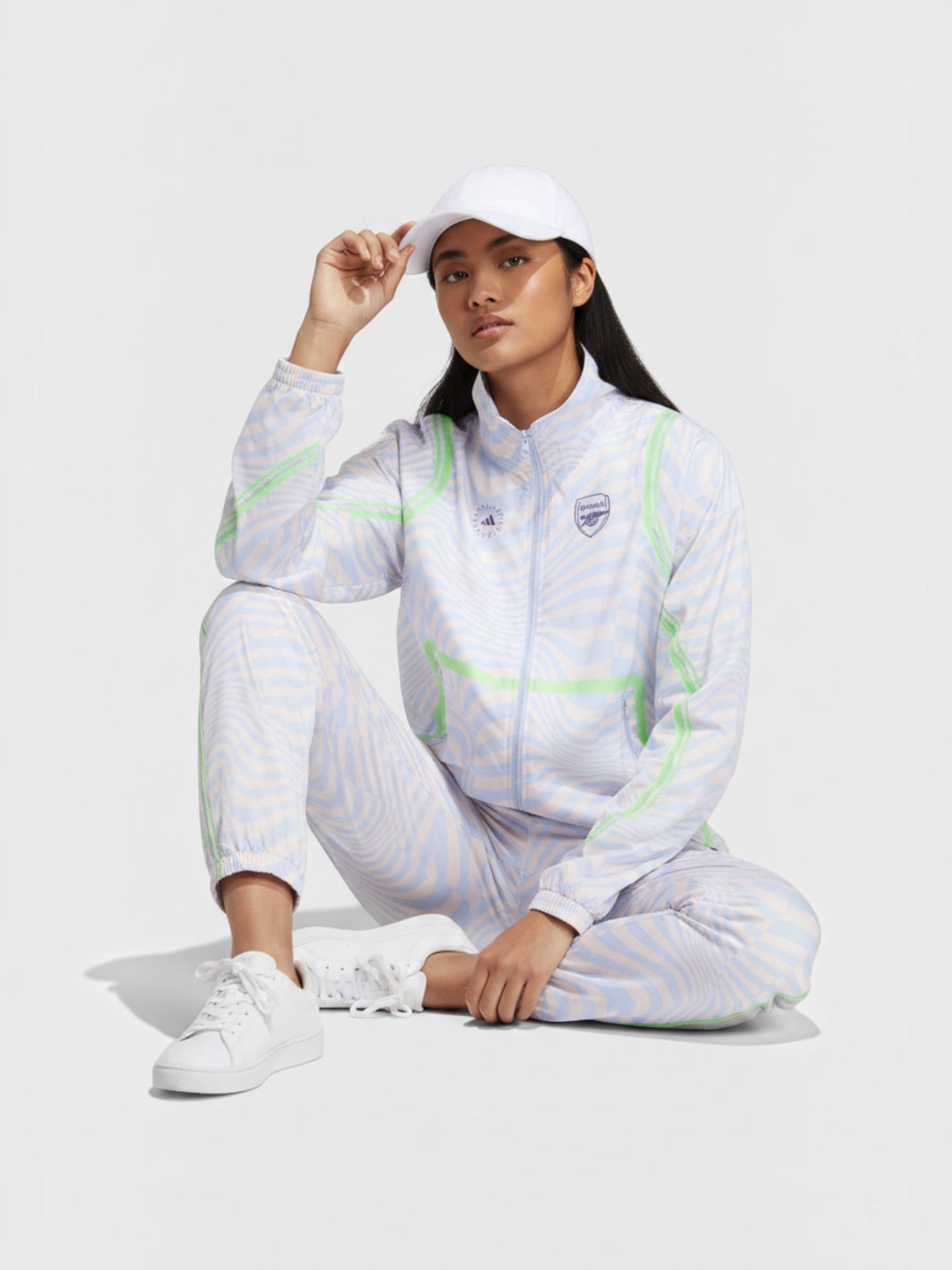 Model mengenakan jaket Adidas Arsenal x Stella McCartney bermotif zebra dengan aksen hijau dan logo tim di dada