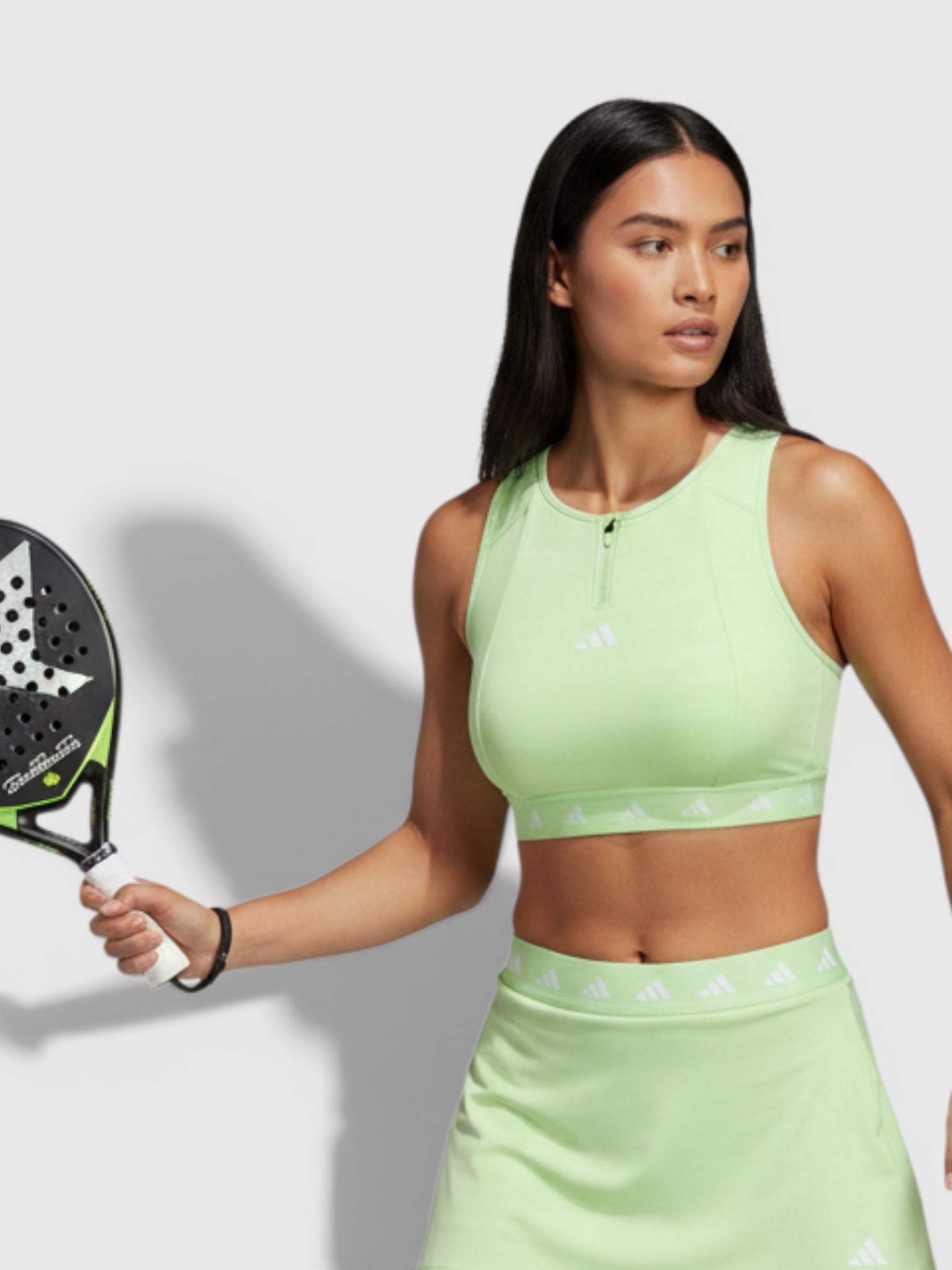 FTFO || BIG BRAND LOW PRICE model wearing a light green Adidas sports bra and matching skirt holding a padel racket