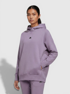 Model wanita mengenakan Adidas W Z.N.E. Overhead Hoodie berwarna ungu muda dengan celana senada dari FTFO || BIG BRAND LOW PRICE