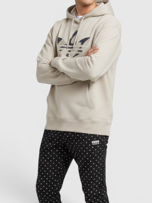 Pria mengenakan hoodie beige Adidas x Marimekko dengan logo grafis di depan, dipadukan celana polkadot dari FTFO || BIG BRAND LOW PRICE