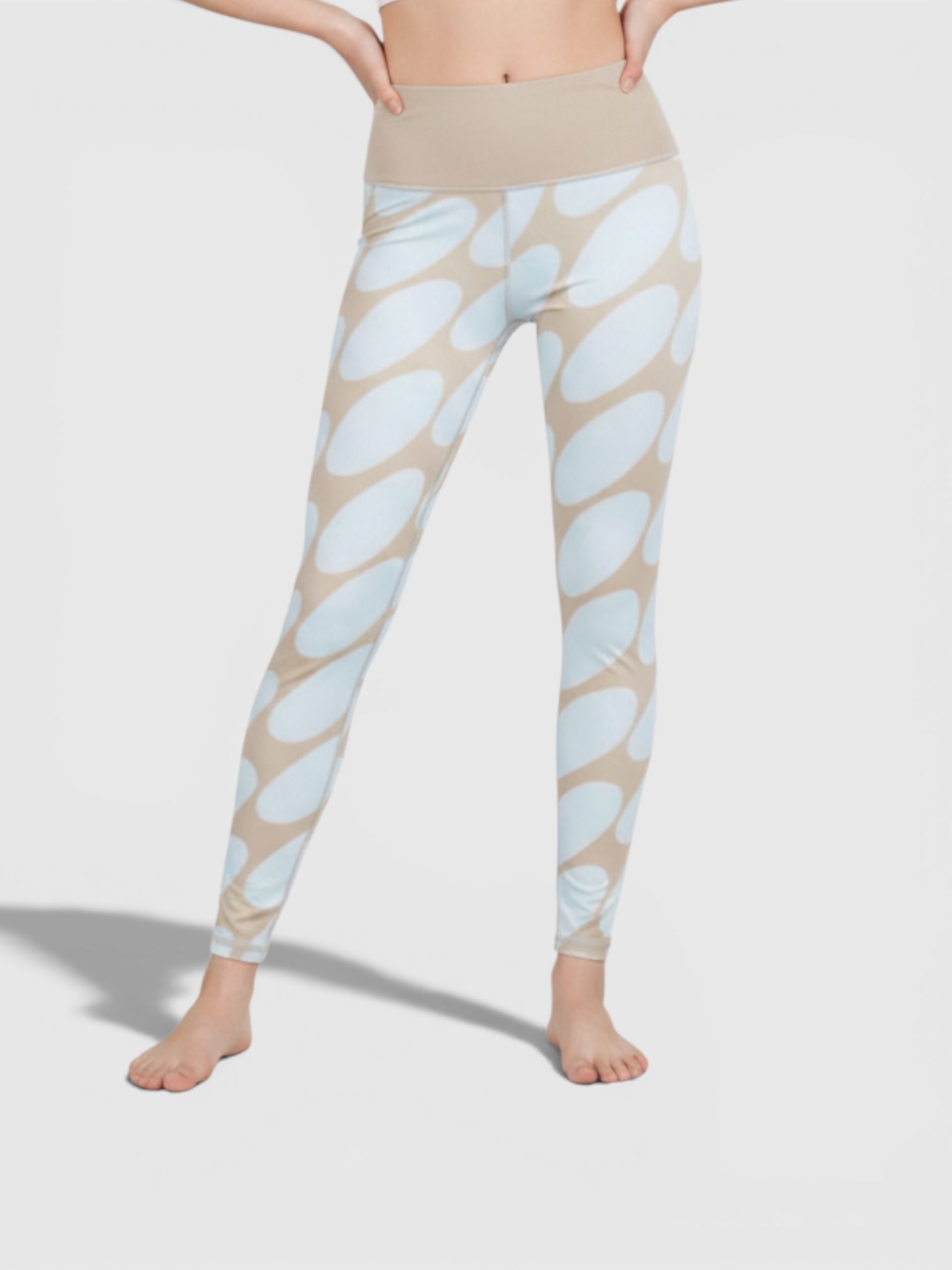 Model mengenakan celana tight Adidas x Marimekko 7/8 bermotif lingkaran biru krem dengan pinggang tinggi yang nyaman