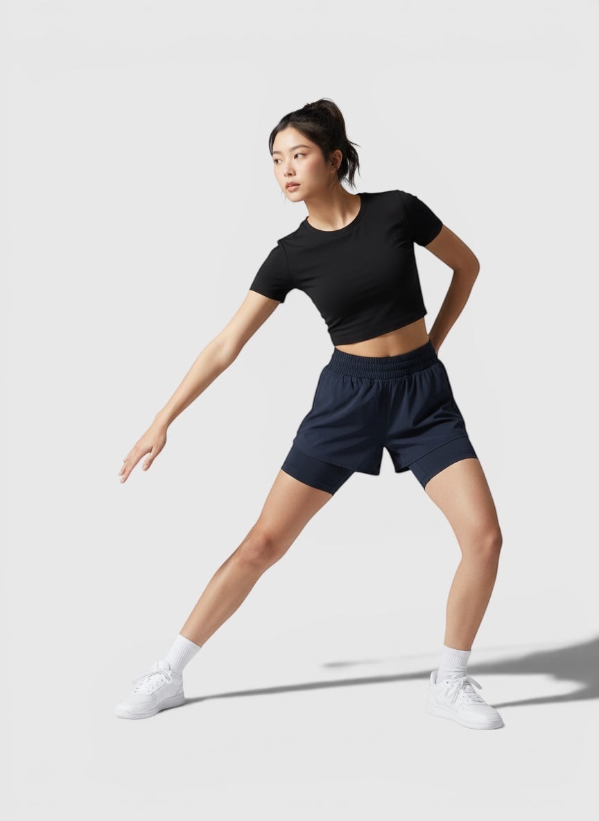 Model wanita mengenakan Adidas Run Icons 3-Stripes running skort berwarna biru tua dengan inner tights yang suportif