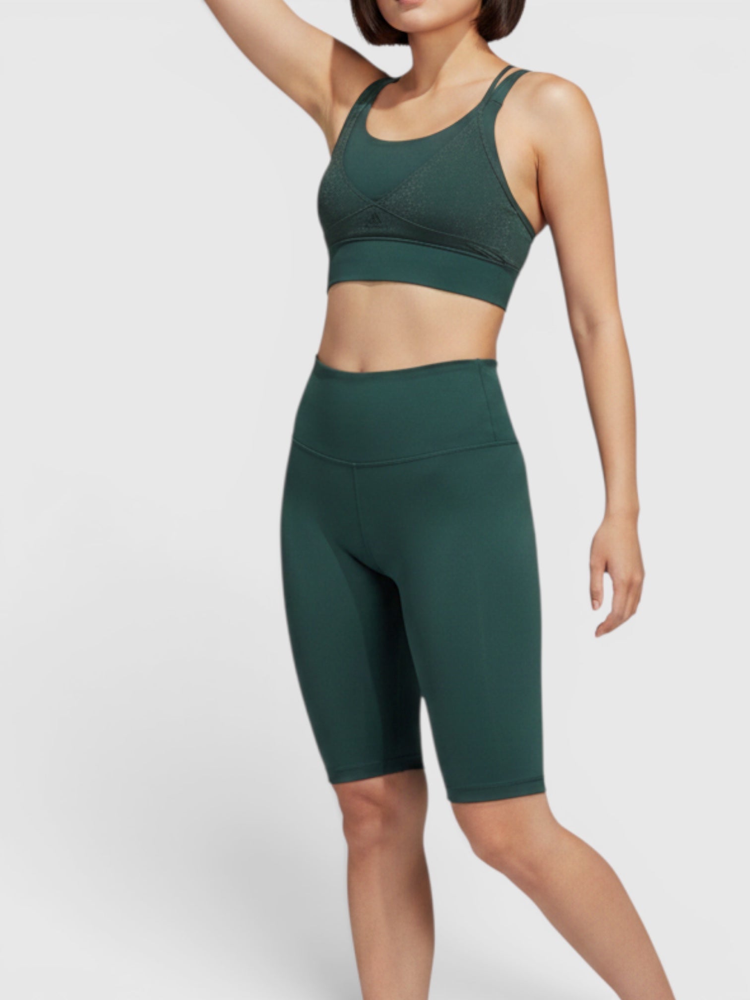 Model mengenakan Adidas Powerimpact sports bra hijau tua dengan celana pendek senada untuk latihan intensitas sedang