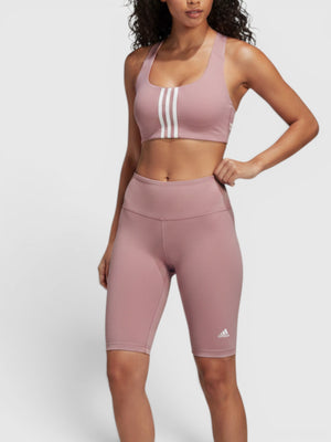 Model mengenakan sports bra Adidas Powerimpact medium-support warna dusty pink dengan aksen tiga garis ikonik