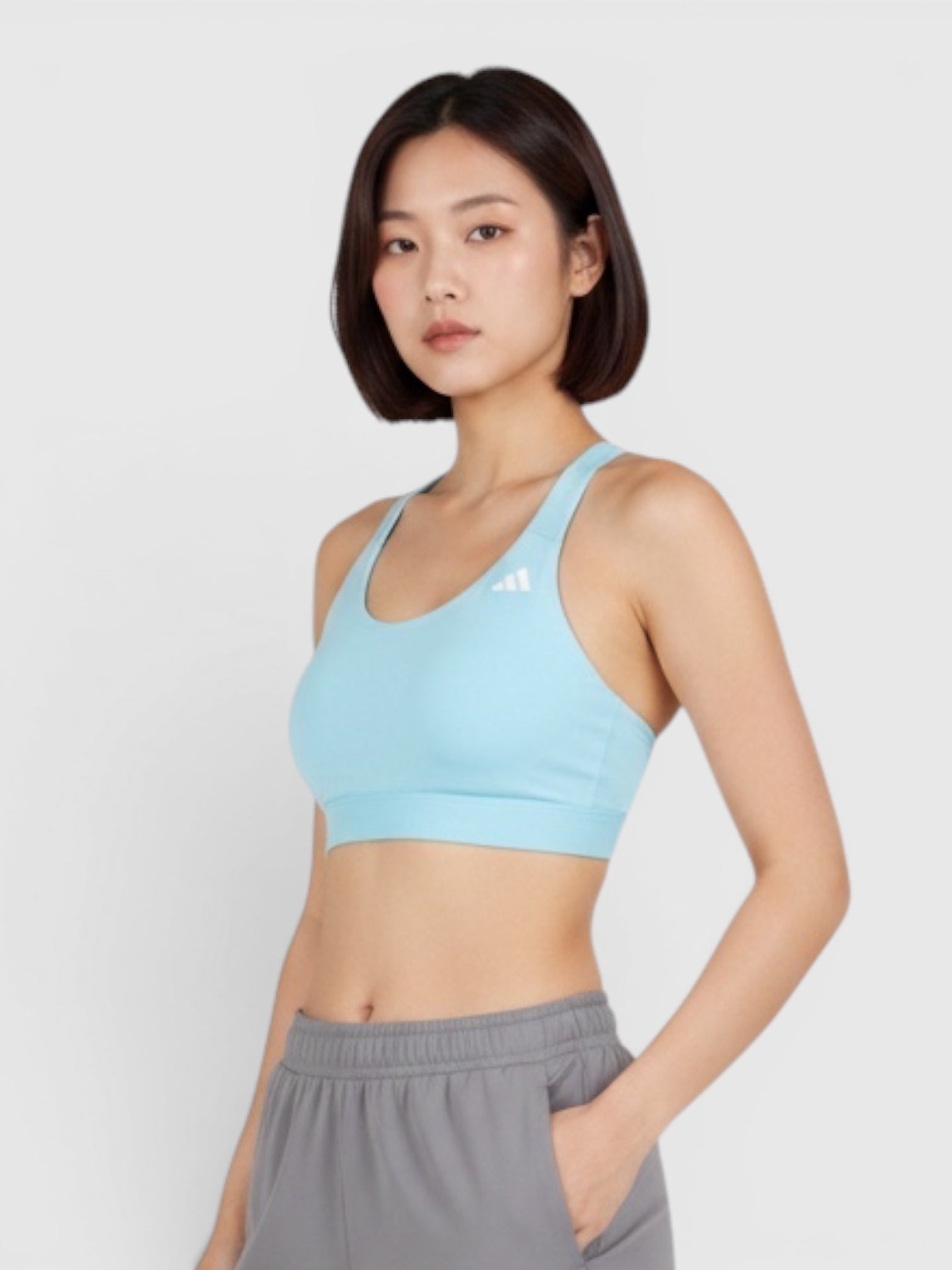 Model wearing a light blue Adidas Ultimate medium-support sports bra and grey joggers from FTFO || BIG BRAND LOW PRICE