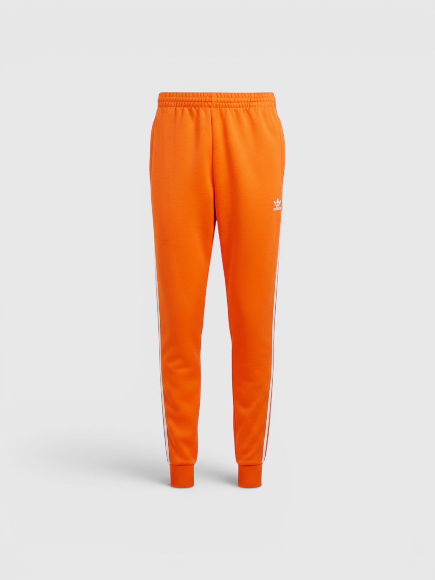 Celana track Adidas Adicolor Classics SST berwarna oranye dengan detail 3-Stripes putih dan logo Trefoil dari FTFO || BIG BRAND LOW PRICE