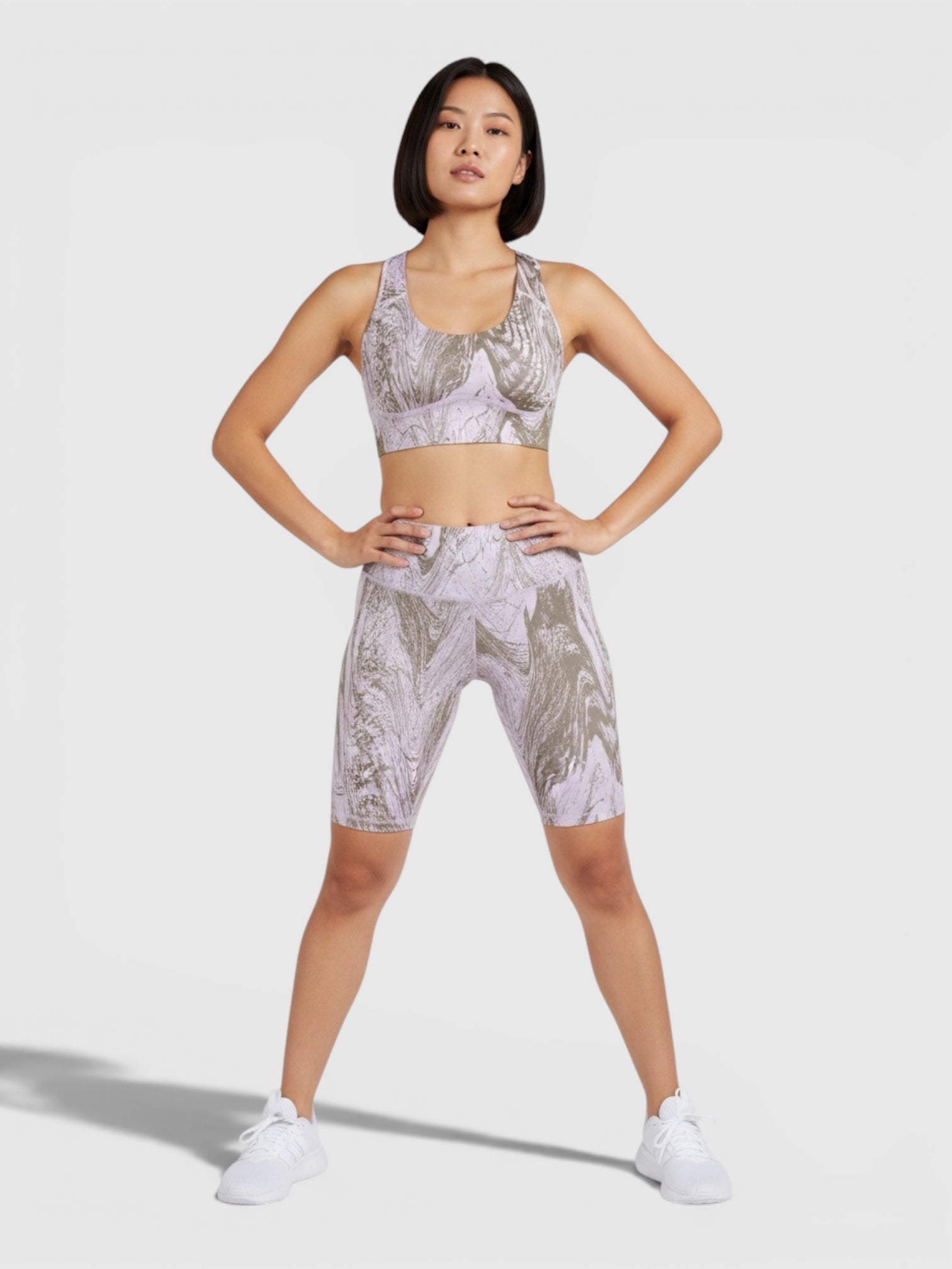 Model mengenakan set olahraga Adidas by Stella McCartney TruePurpose dengan motif marmer ungu dan abu-abu