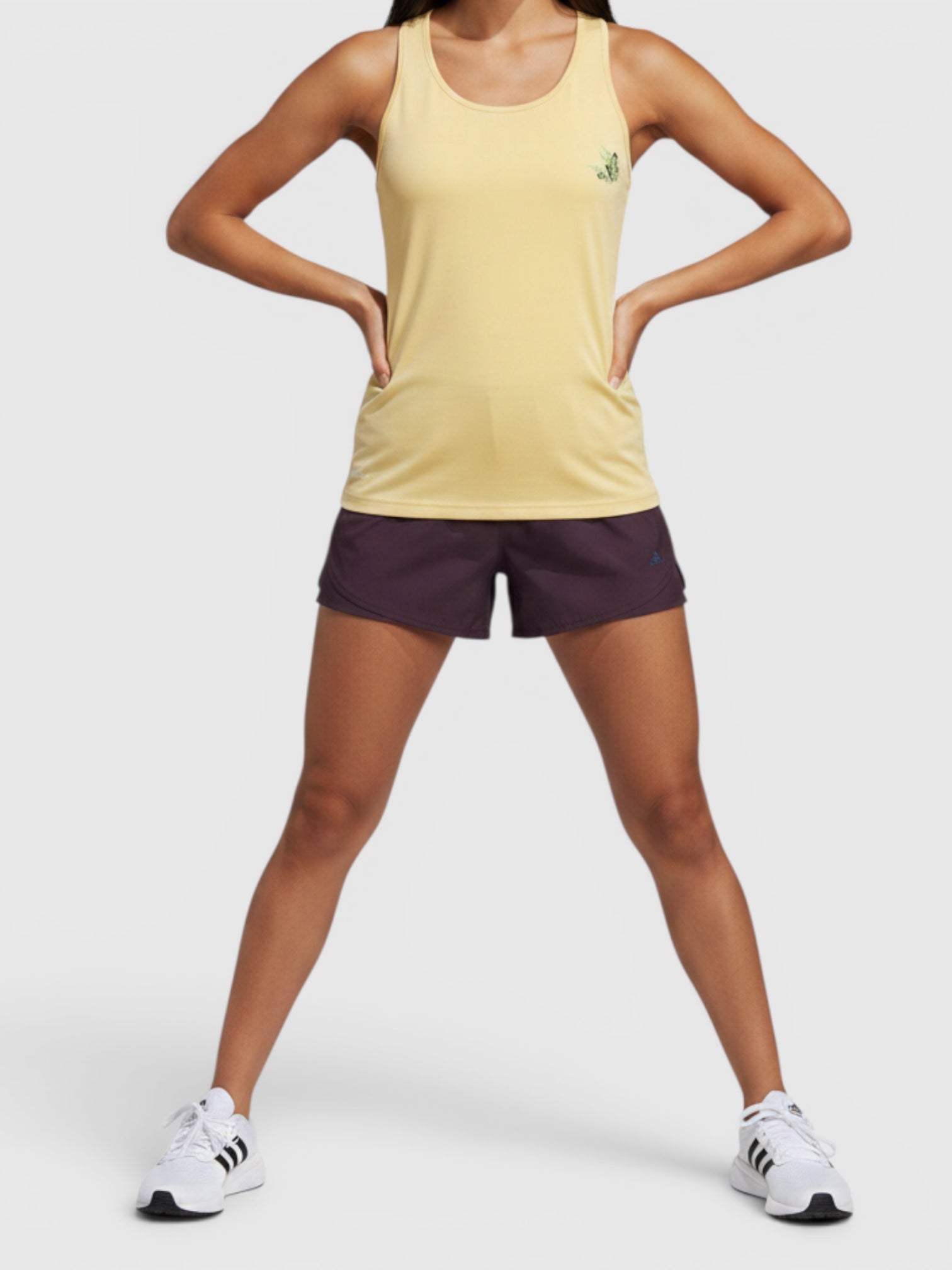 Model mengenakan tank top lari Adidas Earth Day berwarna kuning dengan grafis Cultivate Change dari FTFO || BIG BRAND LOW PRICE