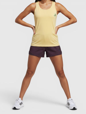 Model mengenakan tank top lari Adidas Earth Day berwarna kuning dengan grafis Cultivate Change dari FTFO || BIG BRAND LOW PRICE