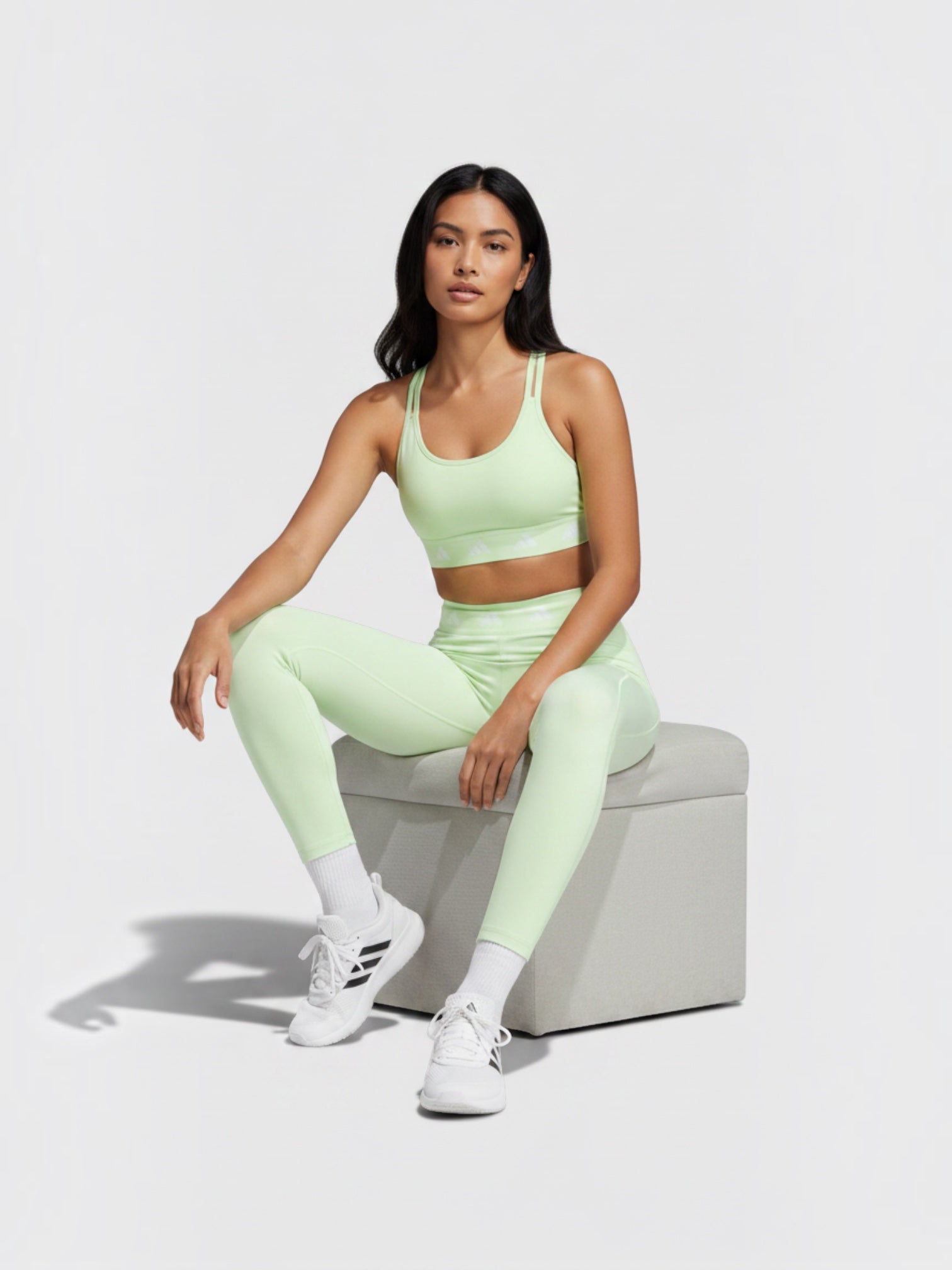 Model mengenakan set olahraga Adidas Techfit warna hijau muda dengan atasan bra dan legging 7/8 yang pas di tubuh