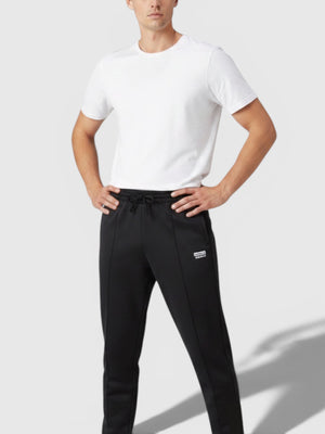 Model pria mengenakan celana jogger hitam Adidas dari FTFO || BIG BRAND LOW PRICE dengan kaos putih dan sepatu kets