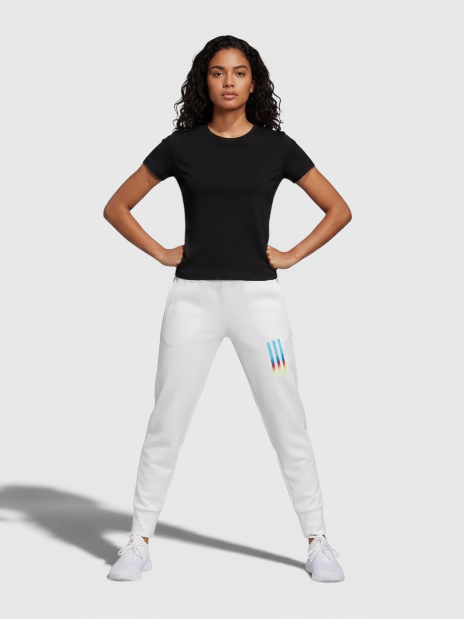 Model mengenakan celana panjang putih FTFO || BIG BRAND LOW PRICE dengan potongan slim fit dan detail logo warna-warni