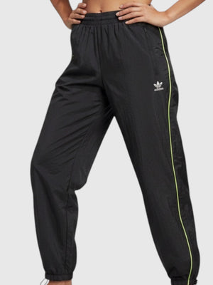 Model wanita mengenakan celana parasut hitam Adidas FR Parachute Pants dengan detail garis neon dari FTFO || BIG BRAND LOW PRICE