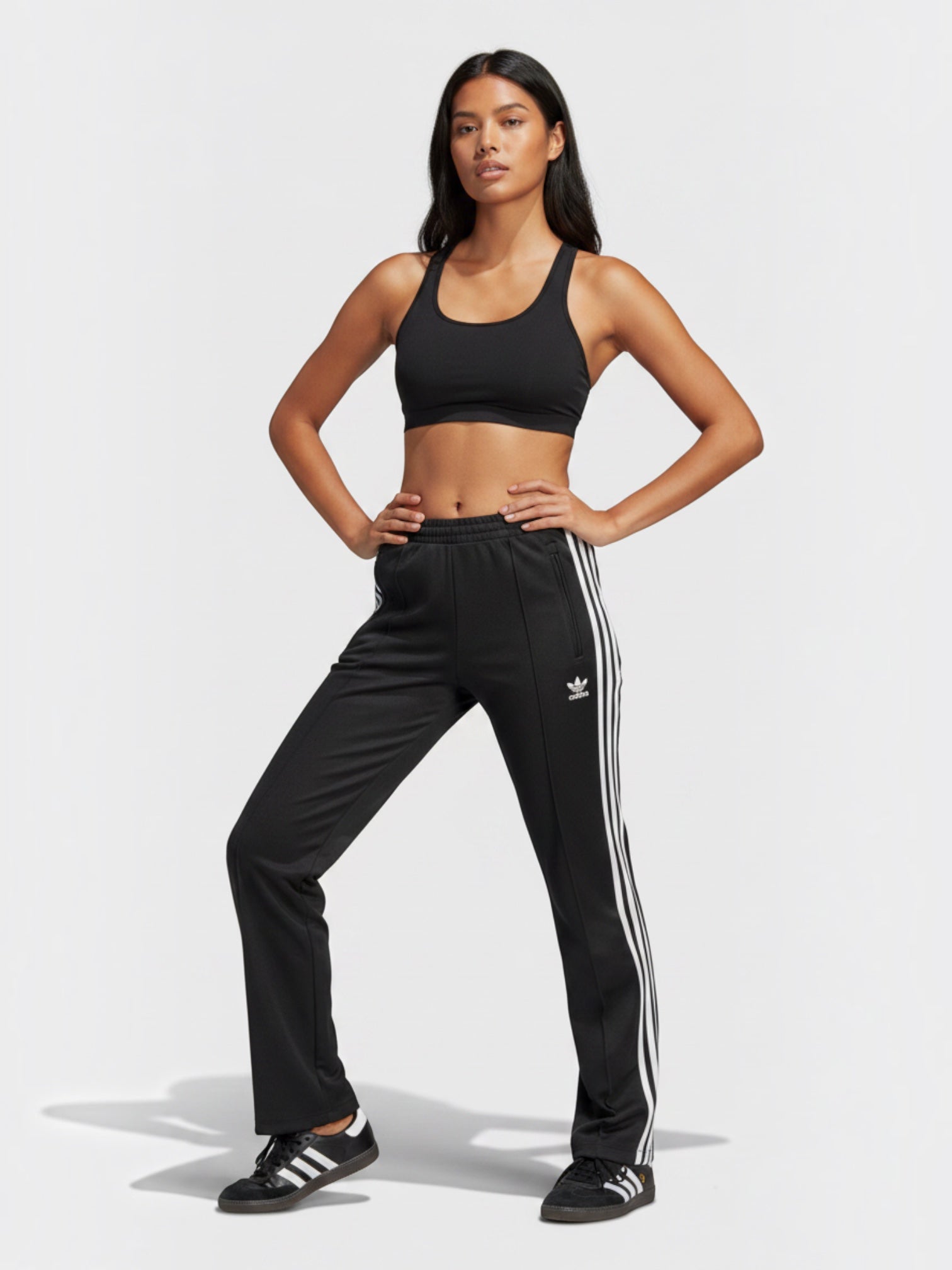 Model wanita mengenakan celana track hitam Adidas SST Pants PB dengan detail 3-Stripes putih dari FTFO || BIG BRAND LOW PRICE