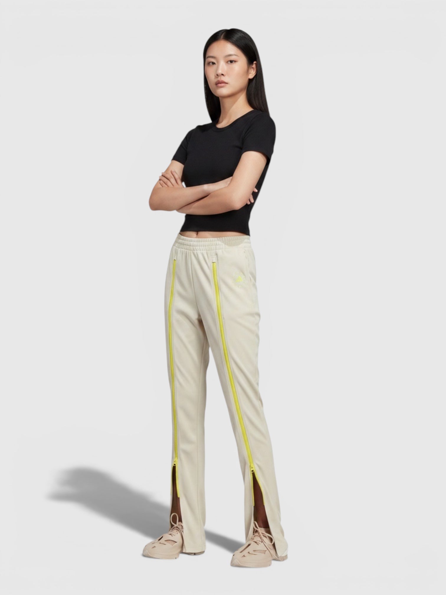 Model mengenakan celana track pants FTFO || BIG BRAND LOW PRICE berwarna krem dengan detail ritsleting neon vertikal