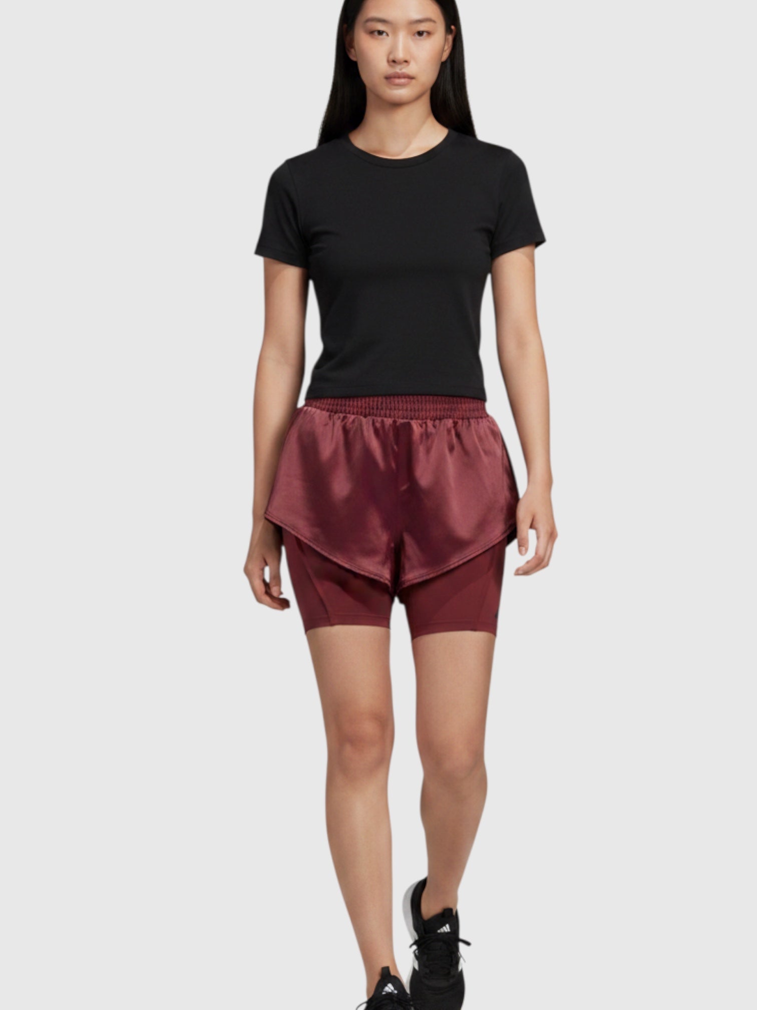 Model mengenakan celana training Adidas Power 2-in-1 berwarna merah marun dengan lapisan dalam tight yang suportif.