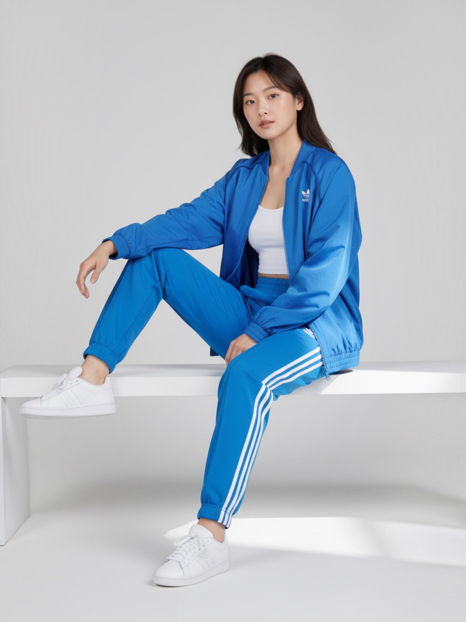 Model wanita mengenakan jaket Adidas Originals FR Track Top biru dengan potongan loose fit dan detail 3-Stripes.