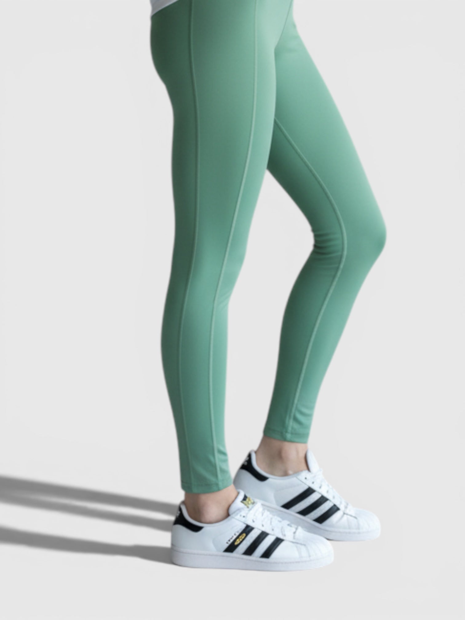 Model mengenakan legging olahraga hijau FTFO || BIG BRAND LOW PRICE dengan kaos putih dan sepatu kets untuk latihan