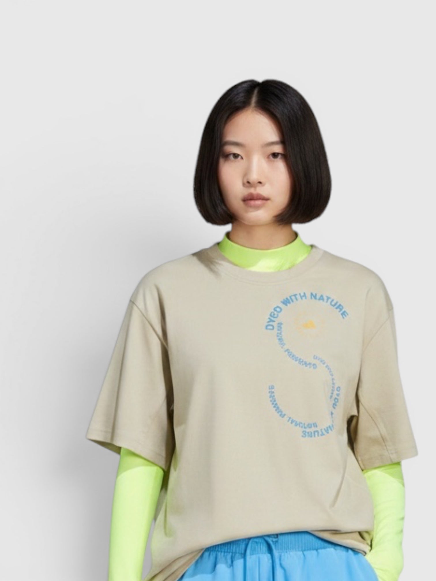 Model wearing FTFO || BIG BRAND LOW PRICE oversized beige graphic t-shirt with neon yellow long sleeves and blue shorts