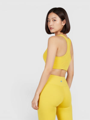 Model mengenakan set olahraga kuning FTFO || BIG BRAND LOW PRICE dengan bra high-support dan celana pendek ketat.