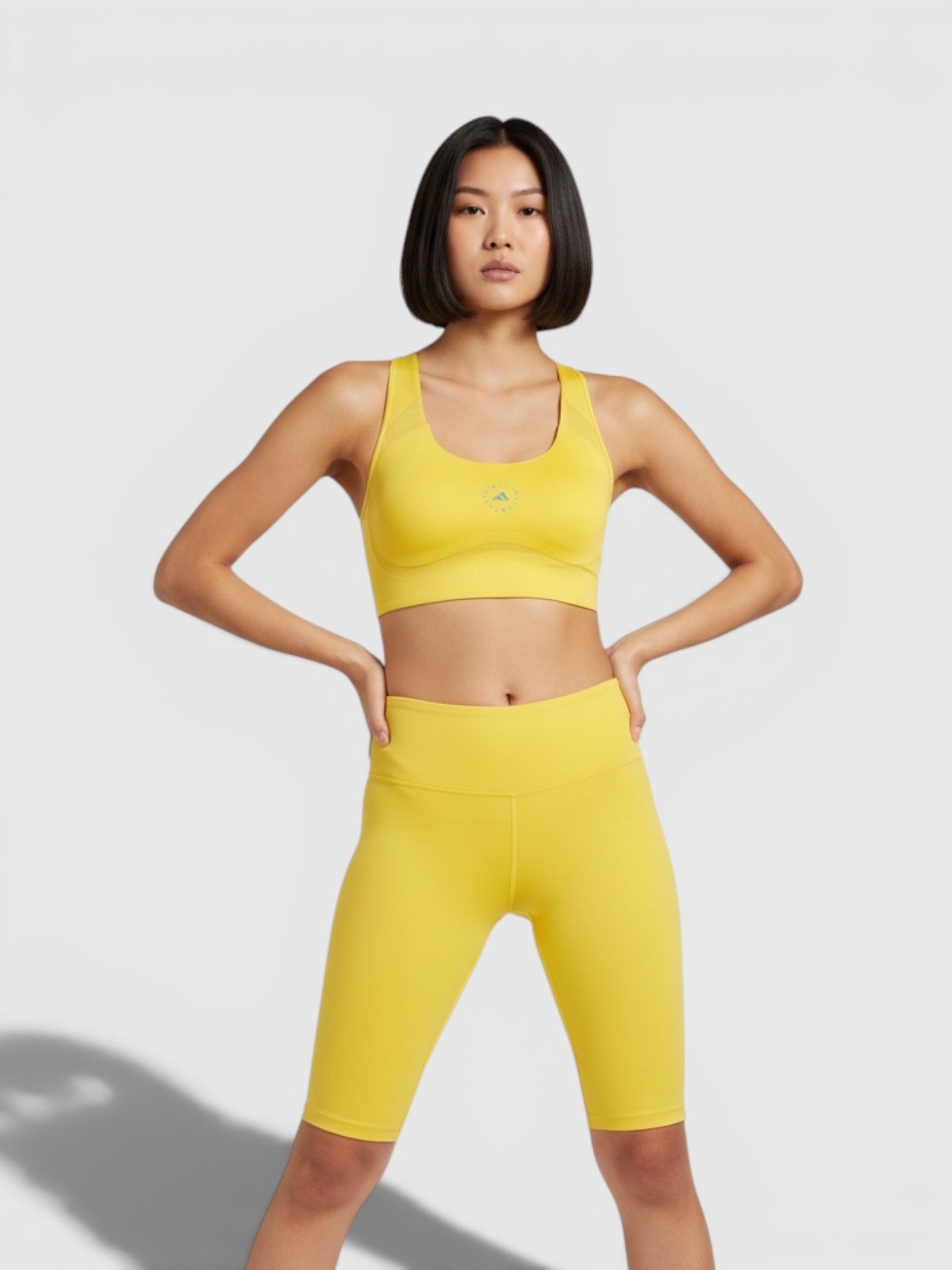 Model mengenakan set olahraga kuning FTFO || BIG BRAND LOW PRICE, bra Adidas by Stella McCartney TruePace high-support.