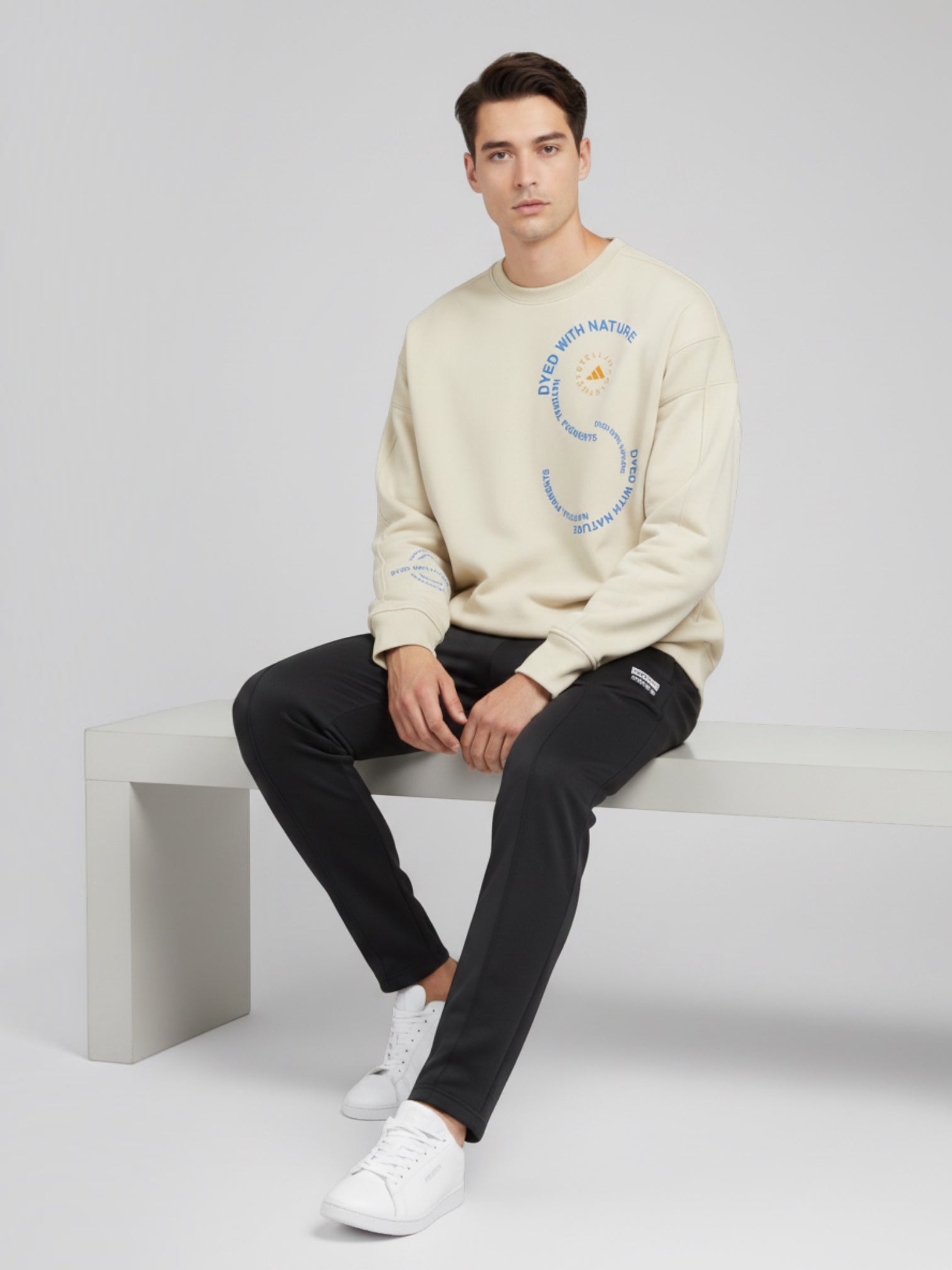 Pria mengenakan sweatshirt oversize krem FTFO || BIG BRAND LOW PRICE dengan grafis melingkar dan logo di dada.